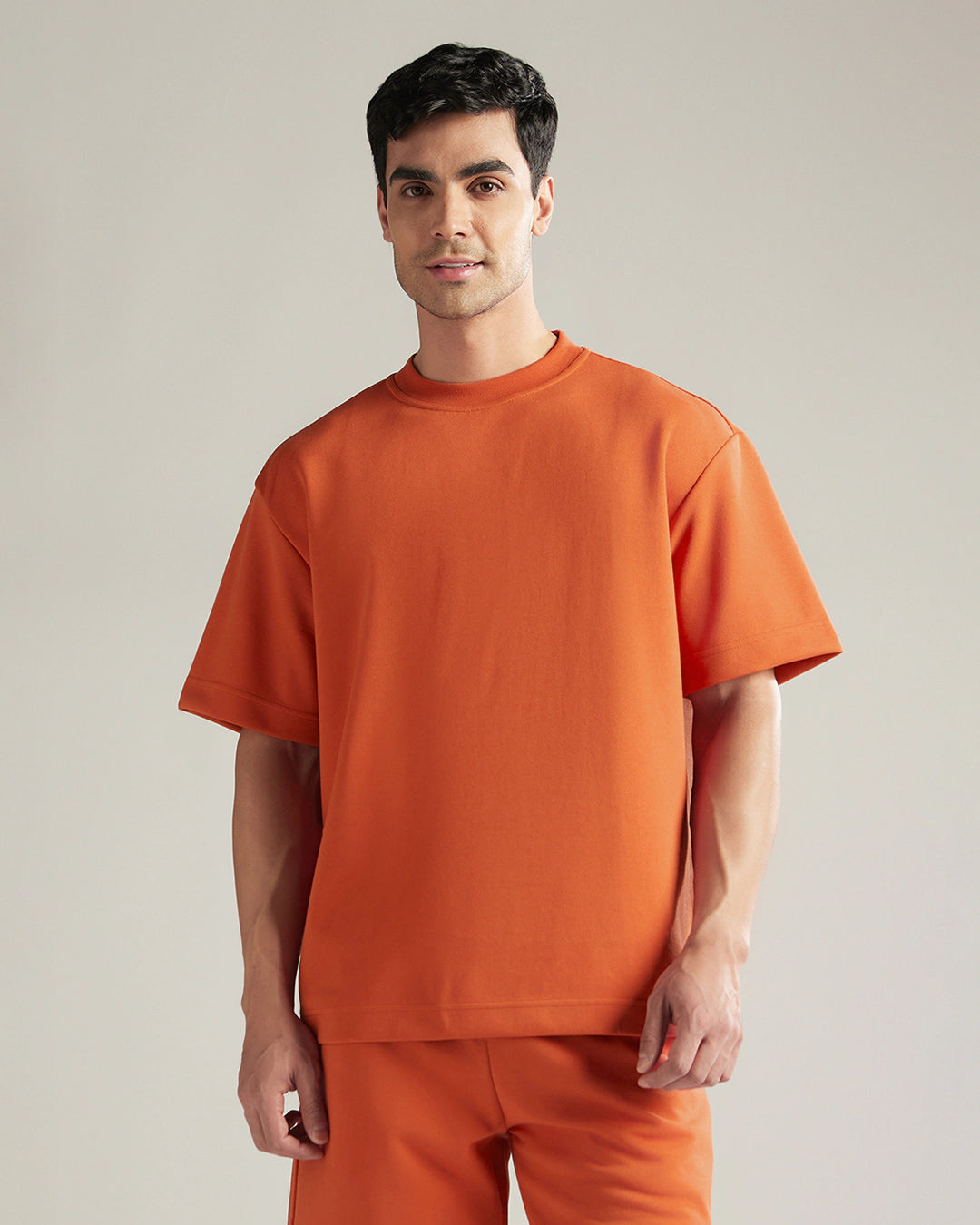 Man wearing an orange outfit against a plain background
