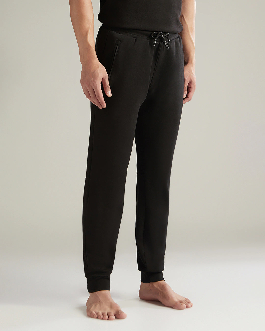 Person wearing black jogger pants on a plain background