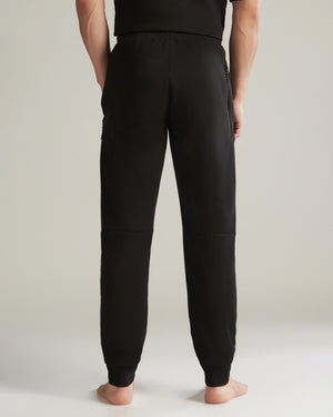 Person wearing black jogger pants on a plain background