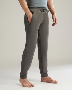 Person wearing gray jogger pants on a plain background