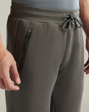 Gray jogger pants with a drawstring and zipper pocket on a neutral background