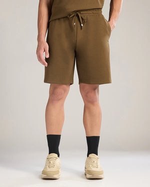 Person wearing brown shorts and black socks on a plain background