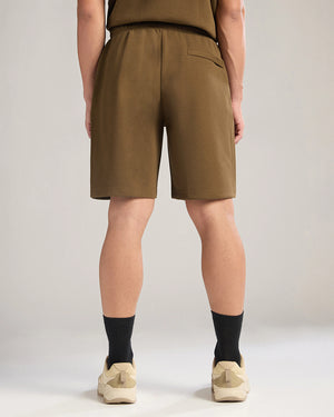 Person wearing brown shorts on a plain background