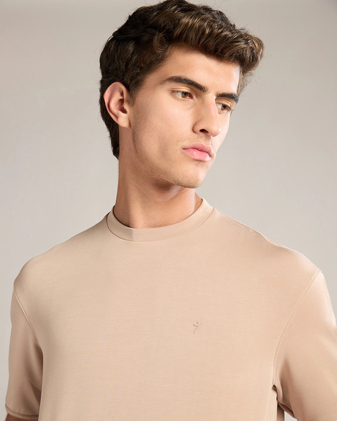 Man wearing a beige sweater against a plain background