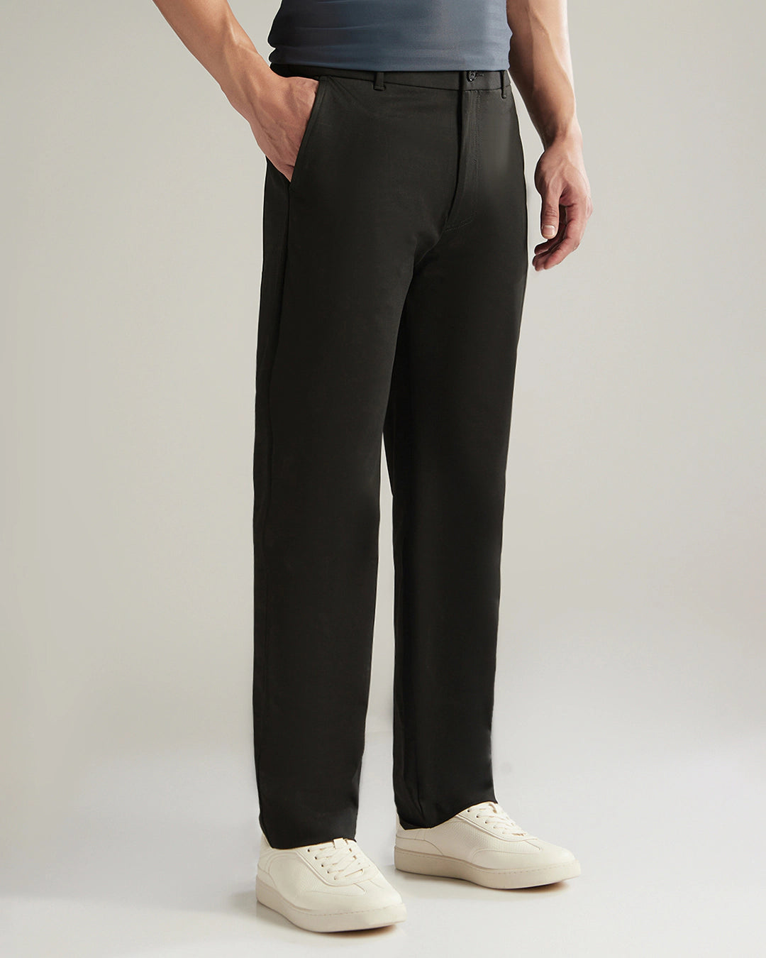 Person wearing black pants and white shoes on a plain background