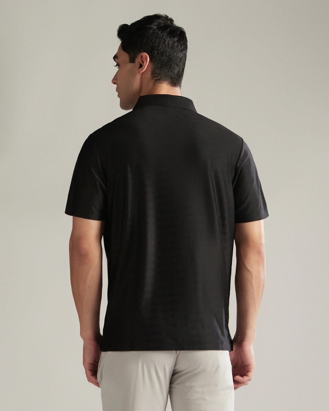 Man wearing a black polo shirt against a plain background