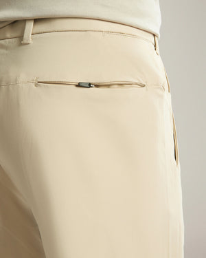 Close-up of beige pants with a zipper detail on a neutral background