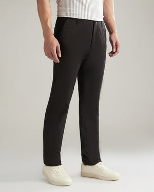 Person wearing black pants and white shoes on a plain background