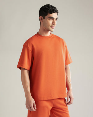 Man wearing an orange outfit against a plain background