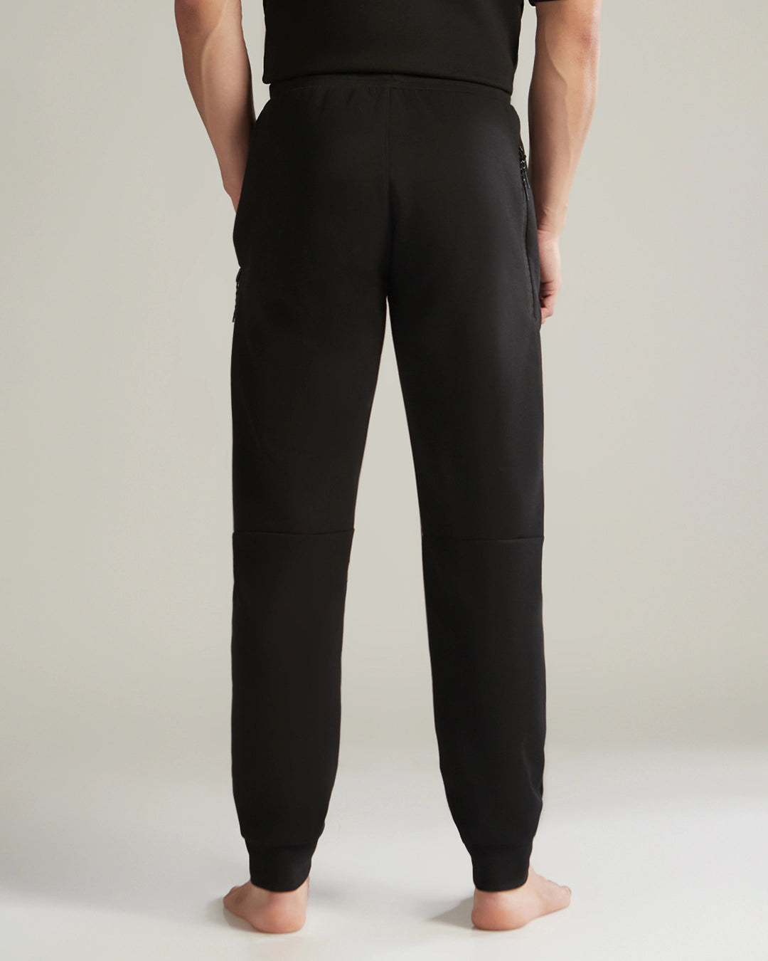 Person wearing black jogger pants on a plain background