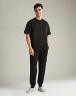 Man wearing a black t-shirt and black pants on a plain background