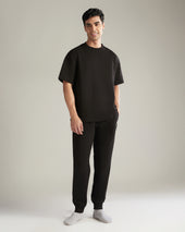 Man wearing a black t-shirt and black pants on a plain background