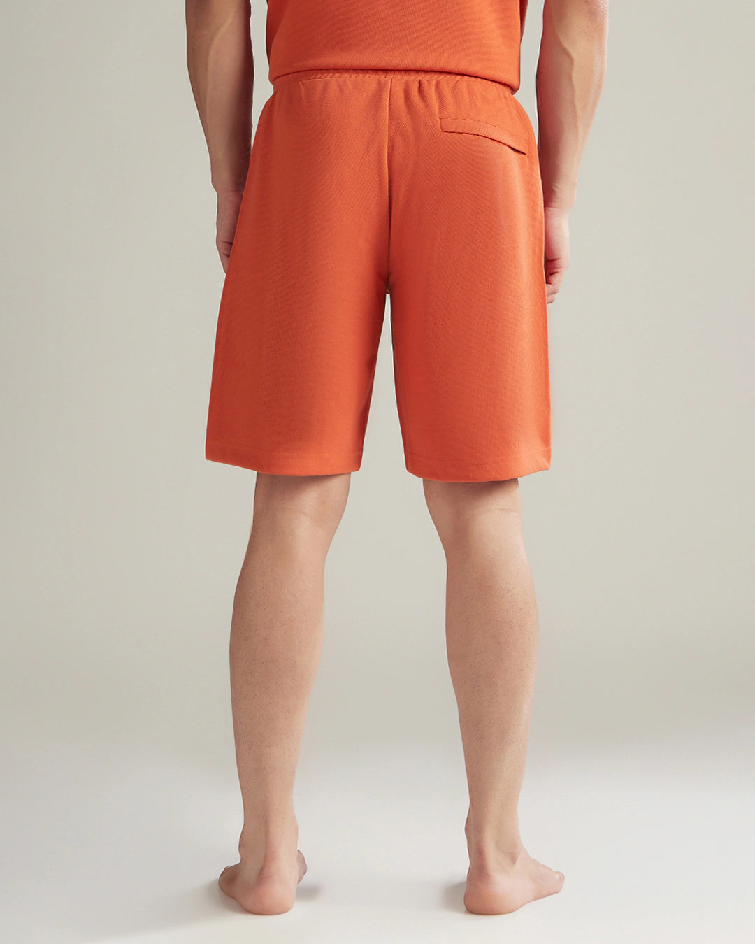 Person wearing orange shorts on a plain background