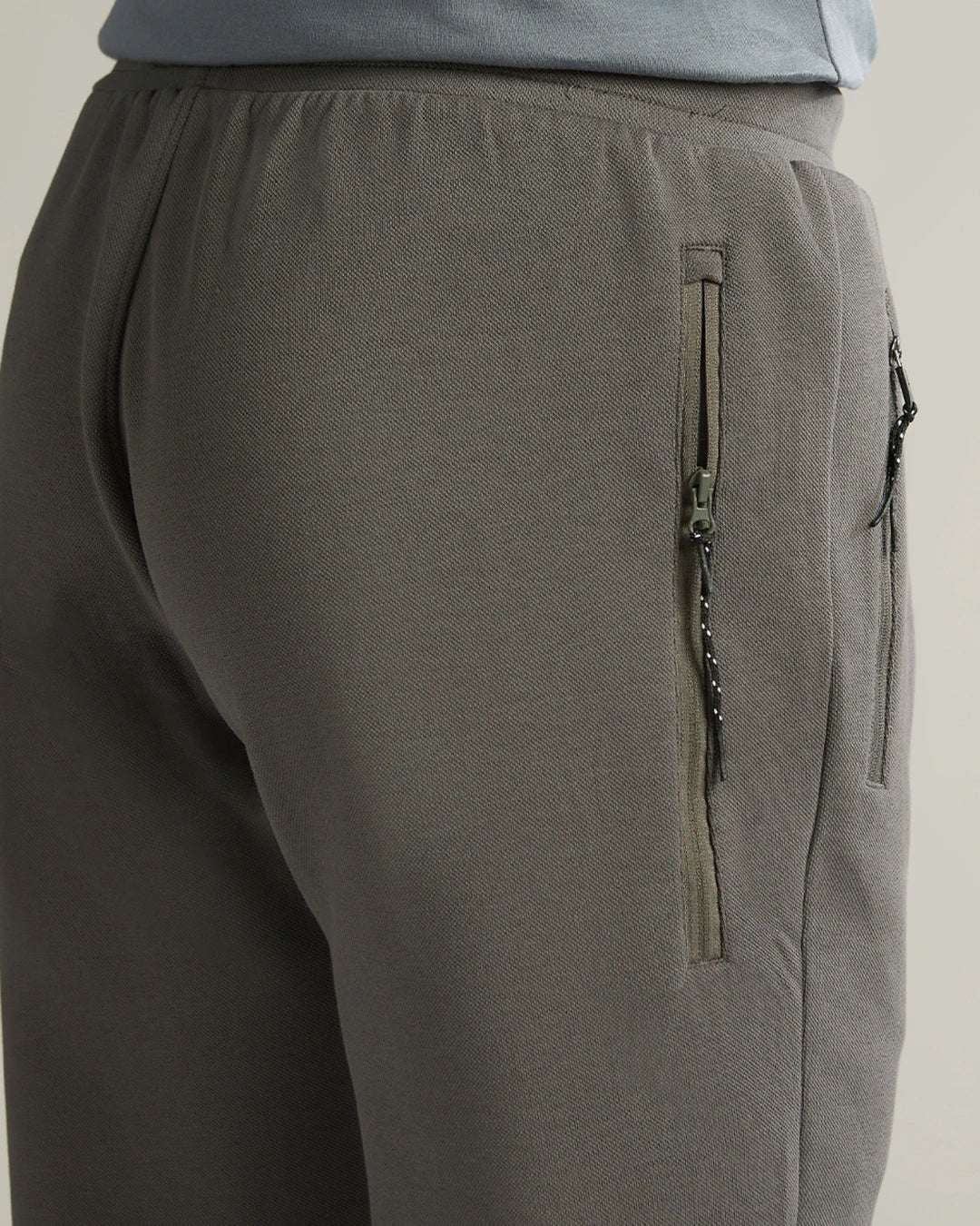 Gray pants with a zipper detail on a neutral background