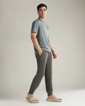 Man wearing a gray t-shirt and dark gray jogger pants against a plain background