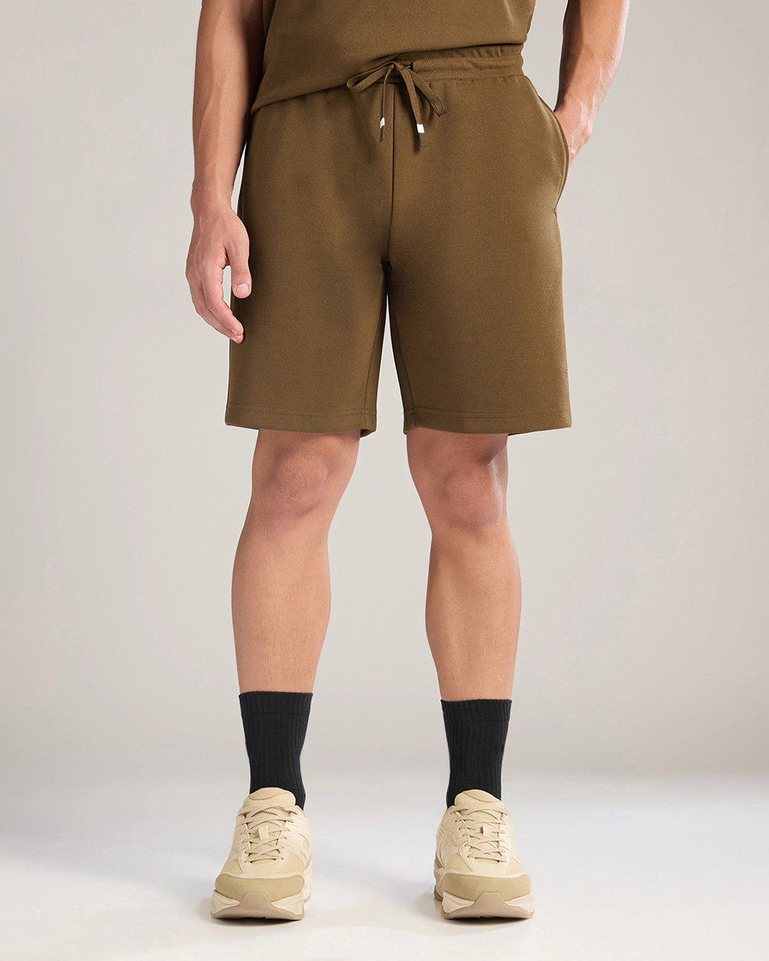 Person wearing brown shorts and black socks on a plain background