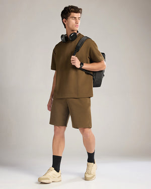 Man wearing a brown outfit with a black backpack on a plain background