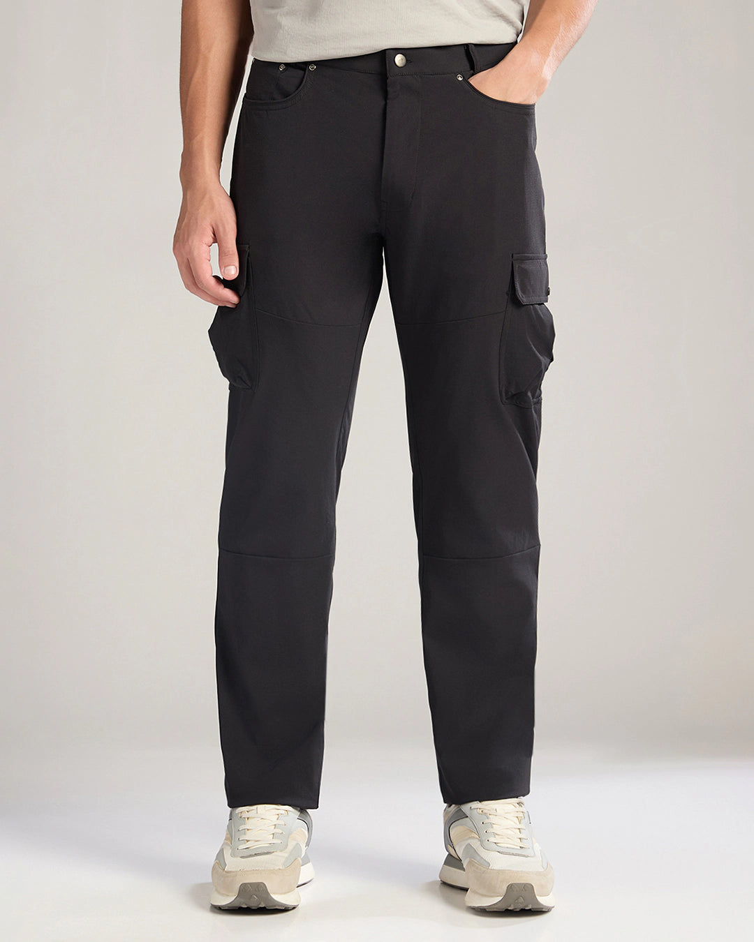 Person wearing black cargo pants on a plain background