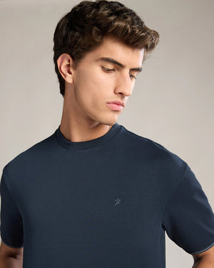 Man wearing a navy blue t-shirt against a neutral background