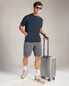 Man in casual attire with a suitcase on a plain background