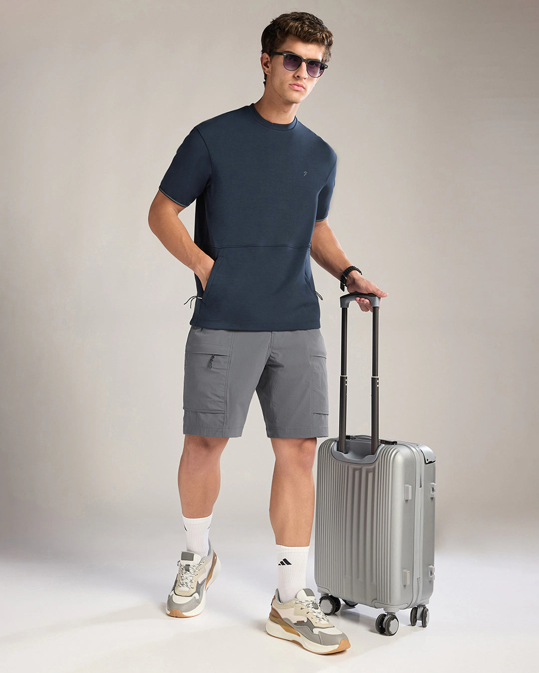 Man in casual attire with a suitcase on a plain background