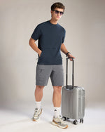 Man in casual attire with a suitcase on a plain background