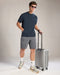 Man in casual attire with a suitcase on a plain background