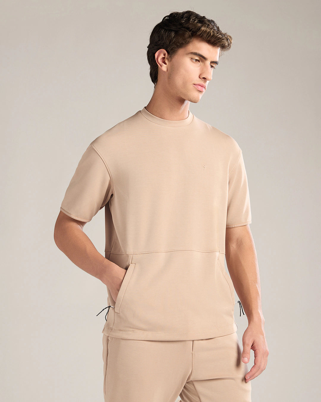 Man wearing a beige outfit against a plain background