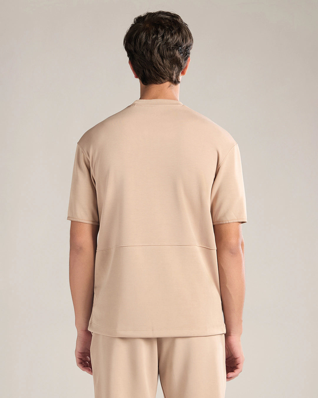 Person wearing a beige outfit on a plain background