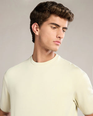 Man wearing a light yellow t-shirt against a neutral background