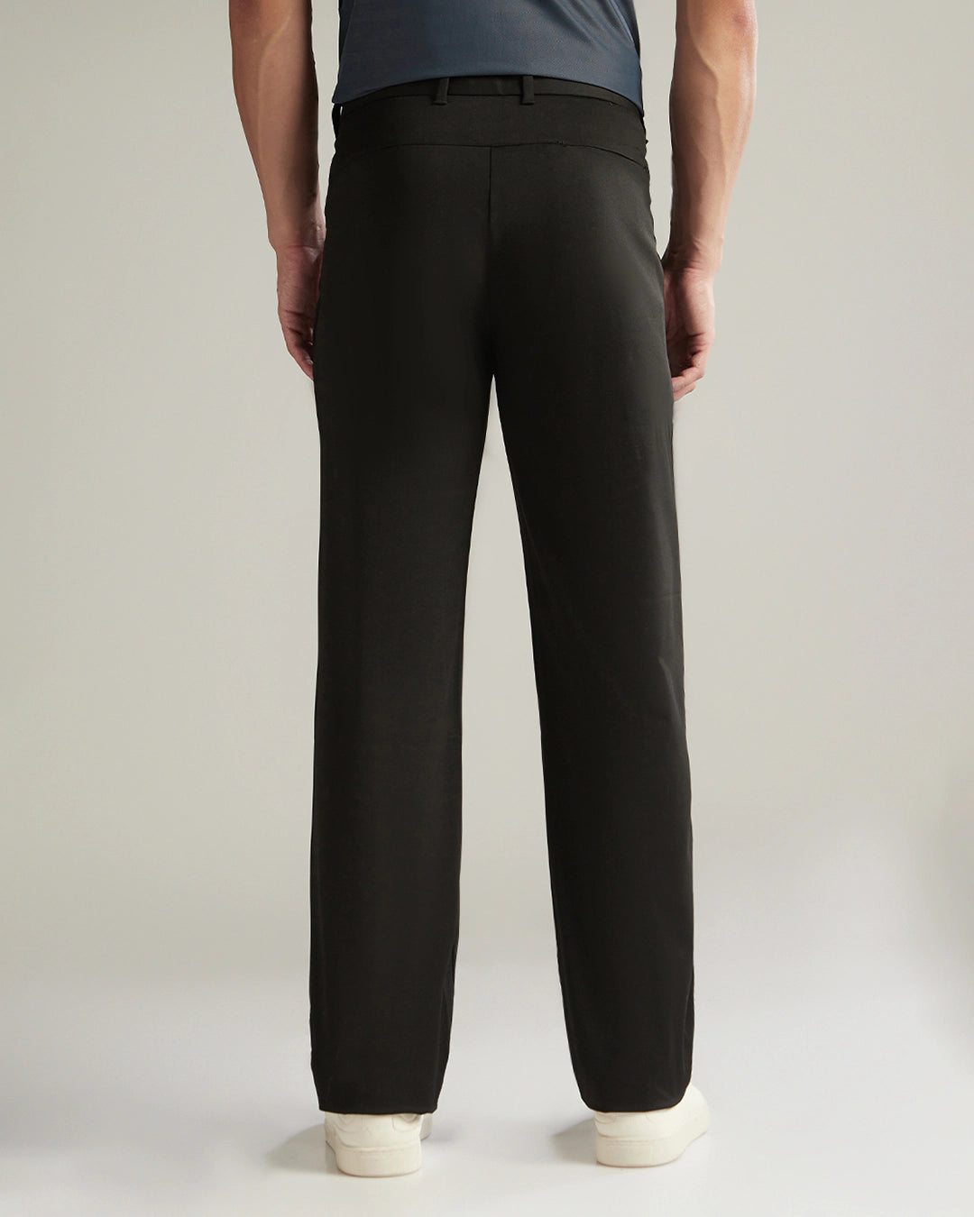 Person wearing black pants on a plain background