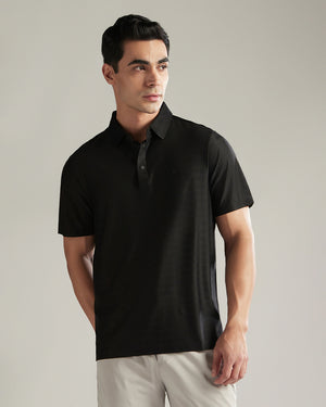 Man wearing a black polo shirt against a neutral background