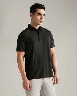 Man wearing a black polo shirt against a plain background