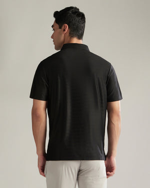 Man wearing a black polo shirt against a plain background