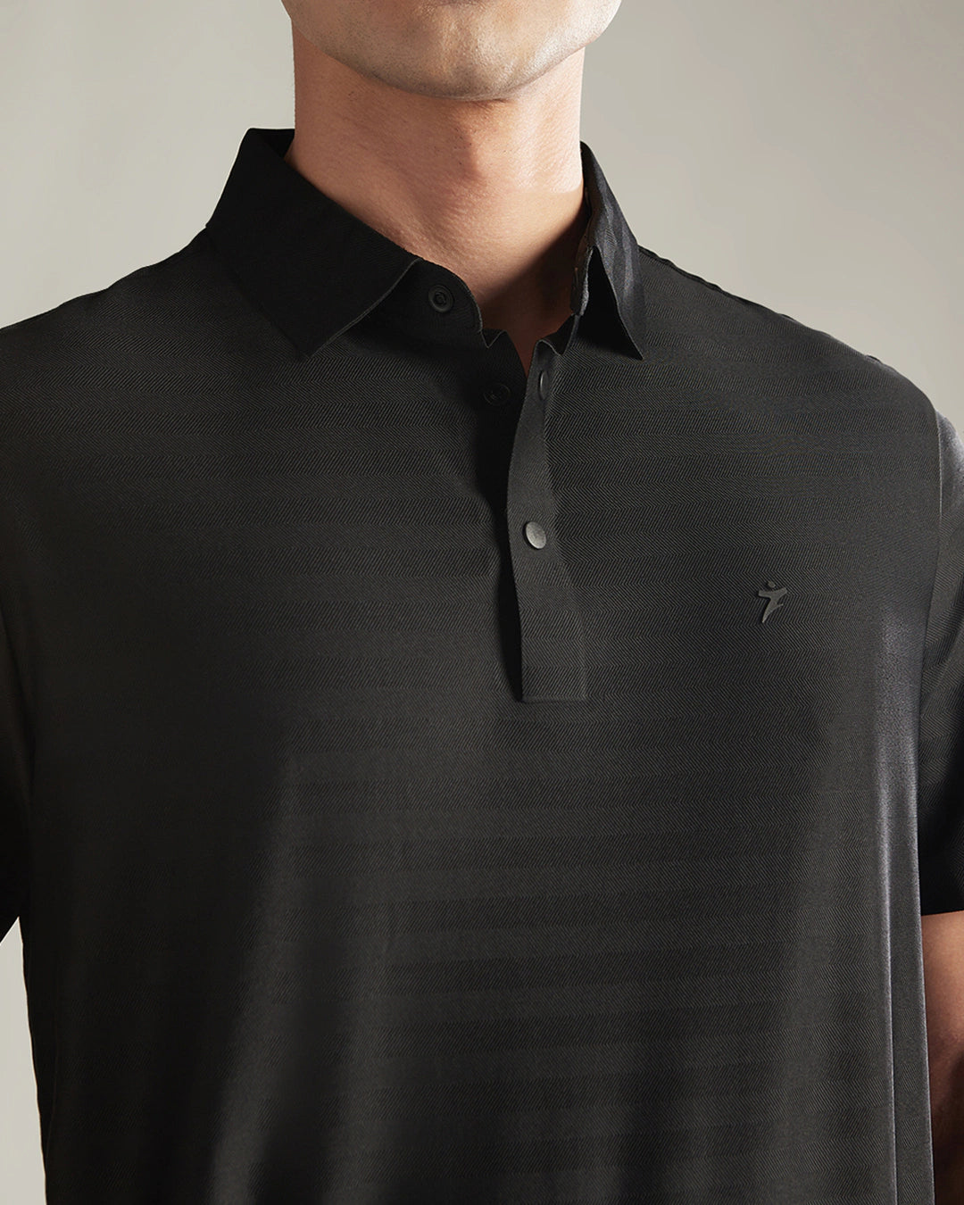 Black polo shirt with a brand logo on a neutral background
