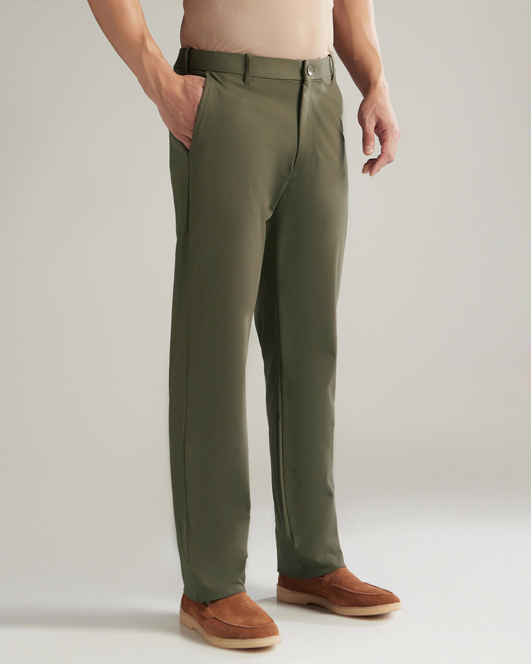 Person wearing olive green pants with a plain background
