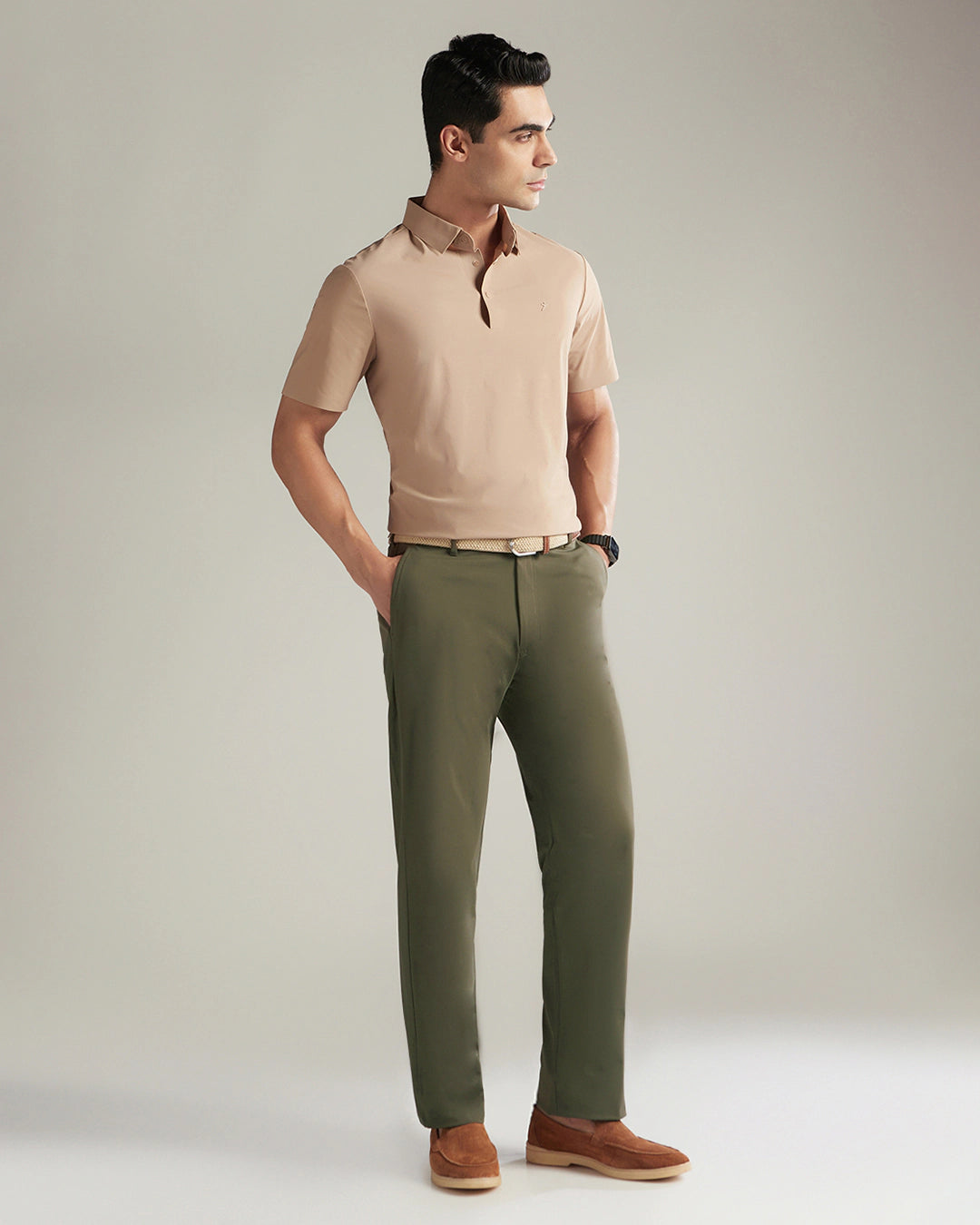 Man wearing a beige polo shirt and green pants against a plain background