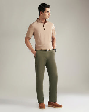 Man wearing a beige polo shirt and green pants against a plain background