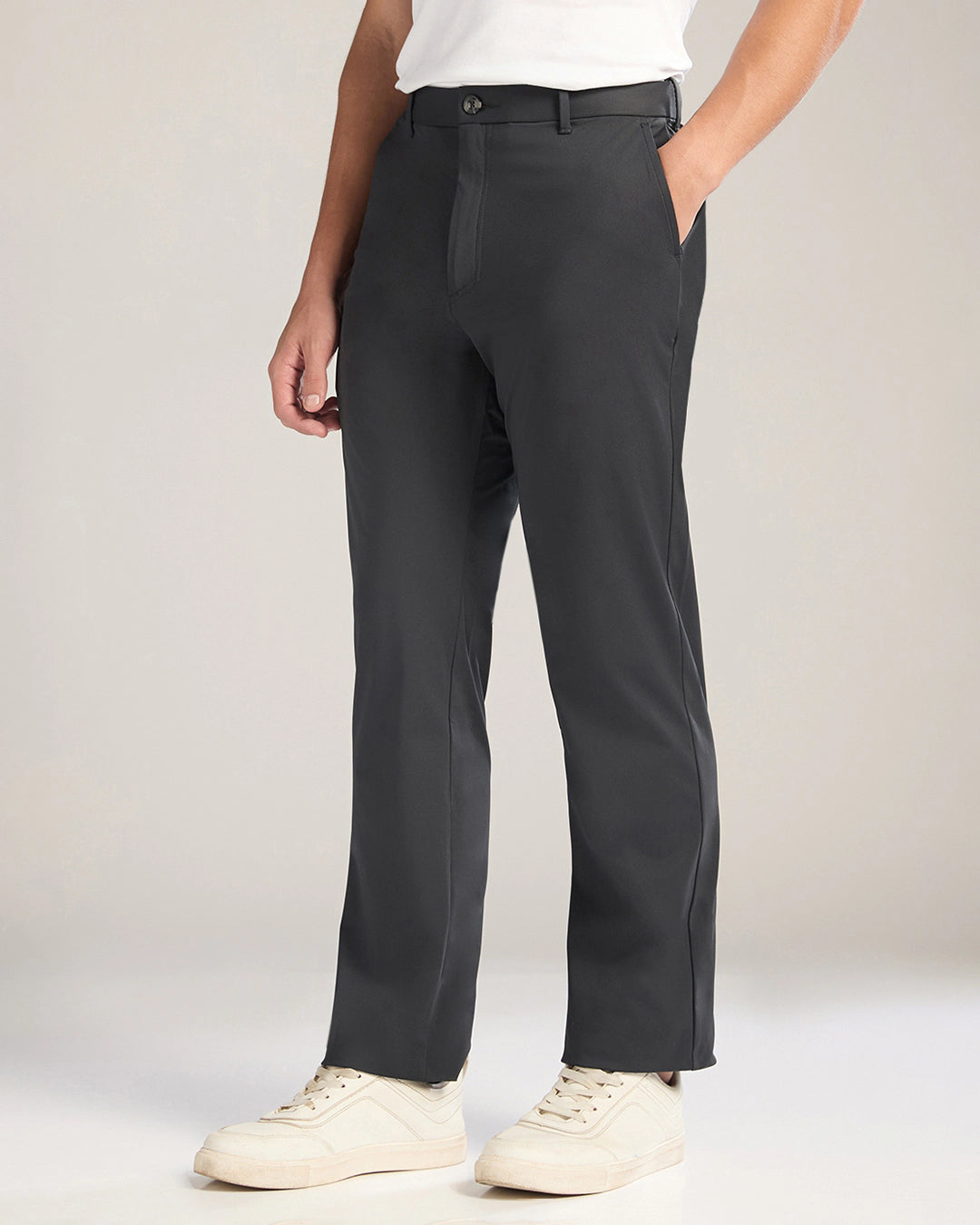 Person wearing black pants and white shoes on a plain background