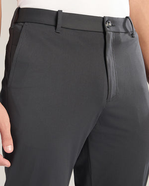 Close-up of dark gray pants with a belt on a neutral background