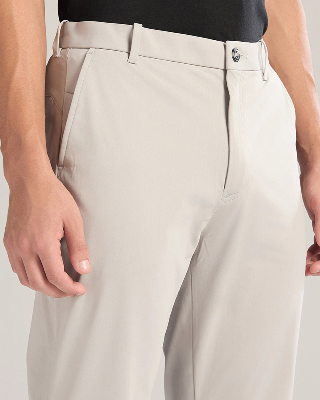 Close-up of beige pants worn by a person on a light gray background