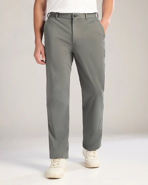 Person wearing gray pants and white sneakers on a plain background
