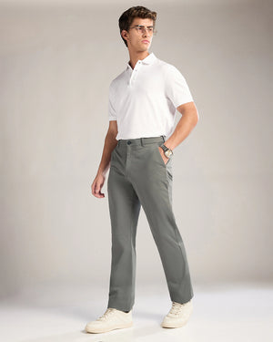 Man wearing a white polo shirt and gray pants against a plain background