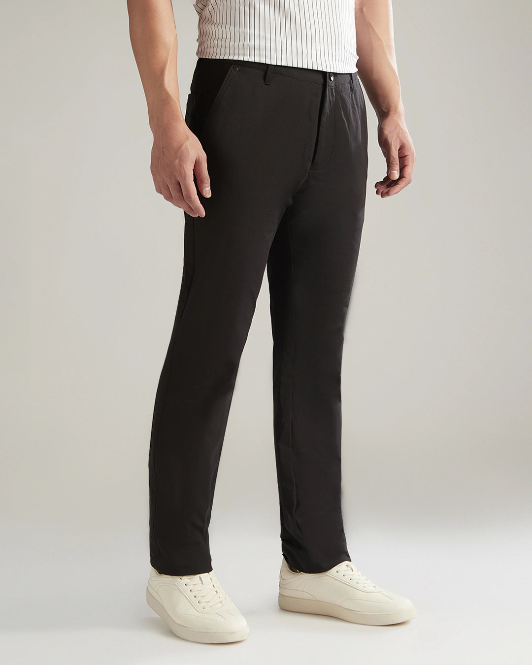 Person wearing black pants and white shoes on a plain background