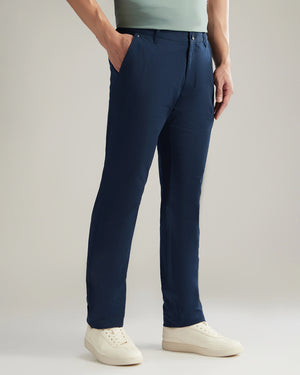 Person wearing navy pants and white shoes on a plain background
